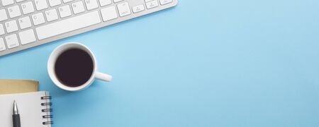 Blue desk office with laptop, smartphone and other work supplies with cup of coffee. Top view with...