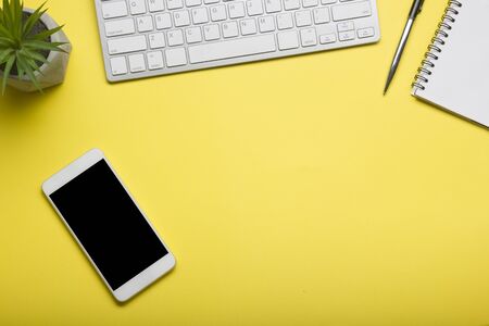 Yellow desk office with laptop, smartphone and other work supplies with cup of coffee. Top view with copy space for input the text. Designer workspace on desk table essential elements on flat layの写真素材