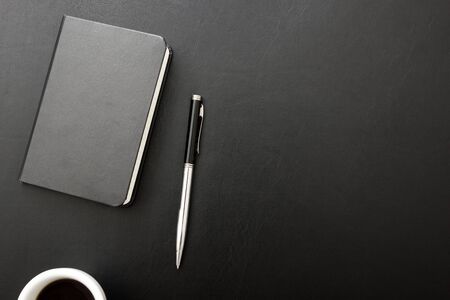 Black desk office with laptop, smartphone and other work supplies with cup of coffee. Top view with...