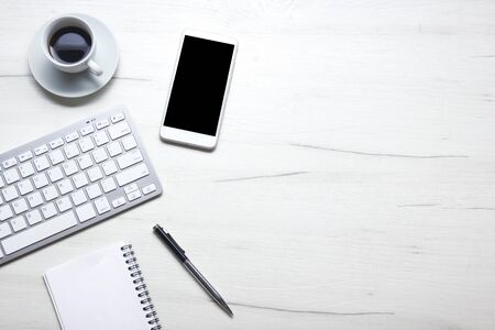 White desk office with laptop, smartphone and other work supplies with cup of coffee. Top view with...