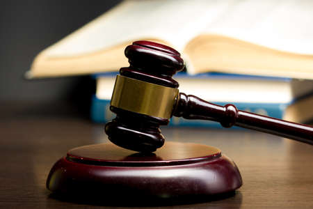 Law concept - Open law book with a wooden judges gavel on table in a courtroom or law enforcement office isolated on white background. Copy space for textの写真素材