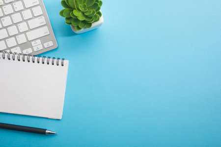 Blue desk office with laptop, smartphone and other work supplies with cup of coffee. Top view with copy space for input the text. Designer workspace on desk table essential elements on flat layの写真素材