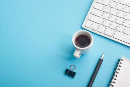 Blue desk office with laptop, smartphone and other work supplies with cup of coffee. Top view with copy space for input the text. Designer workspace on desk table essential elements on flat layの写真素材