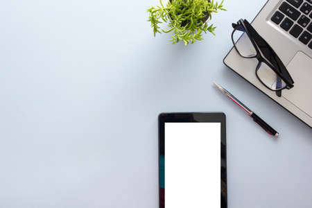 Blue desk office with laptop, smartphone and other work supplies with cup of coffee. Top view with copy space for input the text. Designer workspace on desk table essential elements on flat layの写真素材