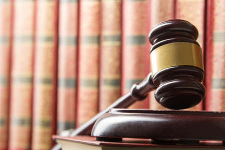 Law concept - Open law book with a wooden judges gavel on table in a courtroom or law enforcement office isolated on white background. Copy space for text.の写真素材