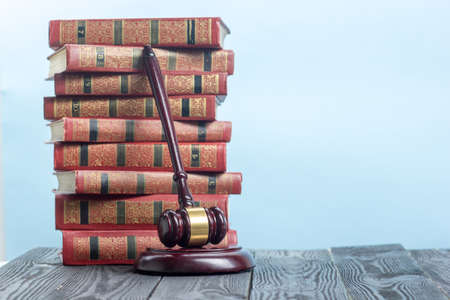 Law concept - Open law book with a wooden judges gavel on table in a courtroom or law enforcement...