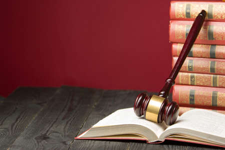 Law concept - Open law book with a wooden judges gavel on table in a courtroom or law enforcement...