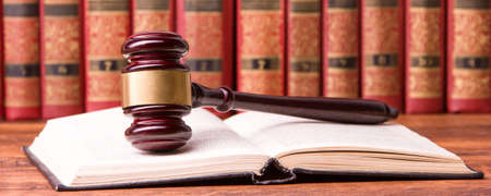 Law concept - Open law book with a wooden judges gavel on table in a courtroom or law enforcement office isolated on white background. Copy space for textの写真素材