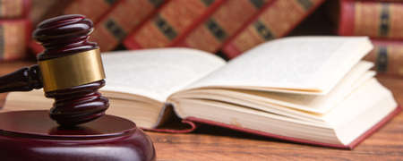 Law concept - Open law book with a wooden judges gavel on table in a courtroom or law enforcement office isolated on white background. Copy space for textの写真素材