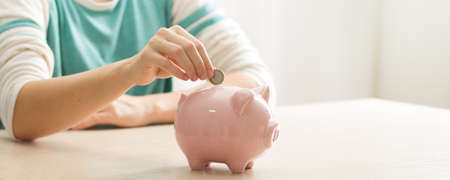 woman hand putting money coin into piggy for saving money wealth and financial concept.