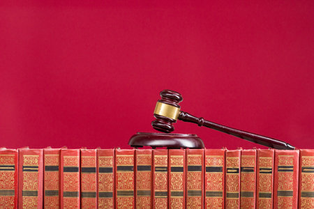 Law concept - Open law book with a wooden judges gavel on table in a courtroom or law enforcement office isolated on white background. Copy space for textの写真素材