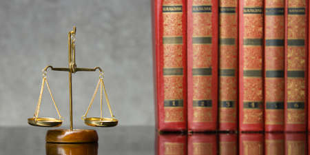 Law concept - Open law book with a wooden judges gavel on table in a courtroom or law enforcement...