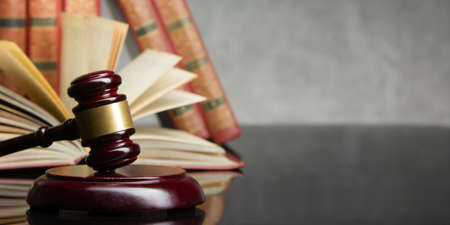 Law concept - Open law book with a wooden judges gavel on table in a courtroom or law enforcement...