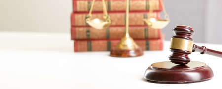 Law concept - Open law book with a wooden judges gavel on table in a courtroom or law enforcement...