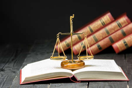 Law concept - Open law book with a wooden judges gavel on table in a courtroom or law enforcement...