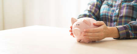 woman hand putting money coin into piggy for saving money wealth and financial concept.の写真素材