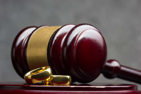 Divorce and separation concept. Two golden wedding rings and judge gavel.の写真素材