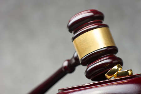 Divorce and separation concept. Two golden wedding rings and judge gavel.の写真素材