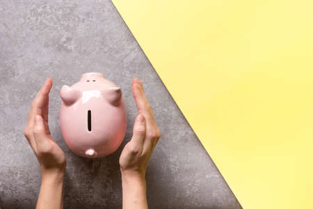 woman hand putting money coin into piggy for saving money wealth and financial concept.の写真素材