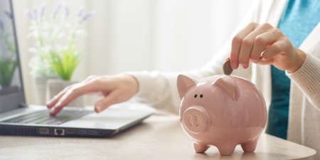woman hand putting money coin into piggy for saving money wealth and financial concept.の写真素材