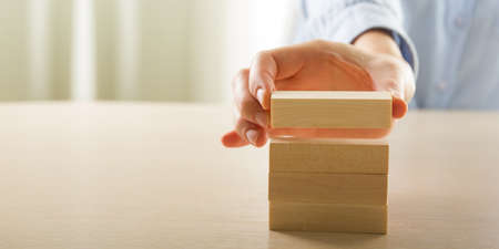 Plan and strategy in business, Risk To Make Business Growth Concept With Wooden Blocks, hand of man has piling up and stacking a wooden blockの写真素材