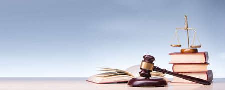 Legal Law and Justice concept - Open law book with a wooden judges gavel on table in a courtroom or law enforcement office. Copy space for text.の写真素材