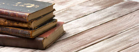Vintage leather books stack on old rustic wooden surfaceの写真素材