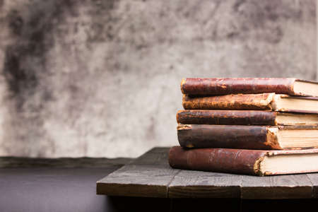 Vintage leather books stack on old rustic wooden surface.の写真素材