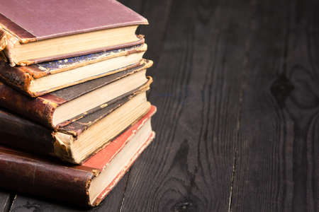 Vintage leather books stack on old rustic wooden surface.の写真素材