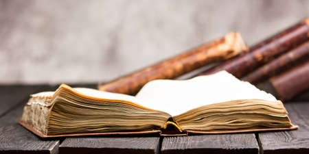 Vintage leather books stack on old rustic wooden surface.