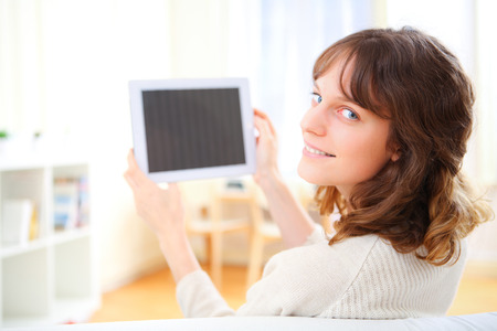 View of a young smiling woman using a tablet on a sofaの写真素材