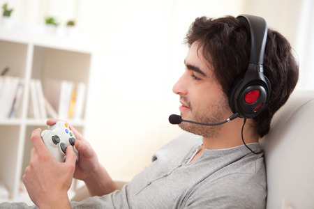View of a Young attractive man playing video games in a sofa の写真素材