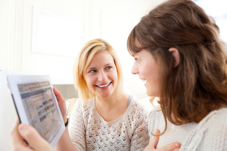 View of Girls choosing their holidays destination on tabletの写真素材