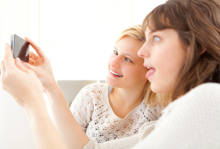 View of Girls on sofa taking selfie picture with smartphoneの写真素材
