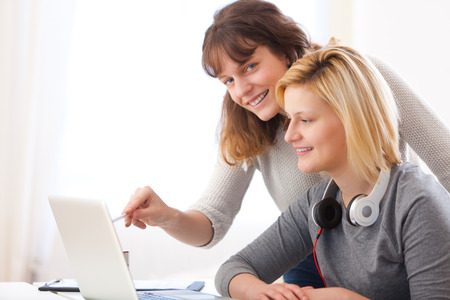 View of a Young teacher assist a student during her homeworkの写真素材