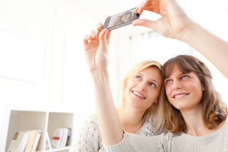 View of Girls on sofa taking selfie picture with smartphoneの写真素材