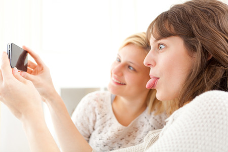 View of Girls on sofa taking selfie picture with smartphoneの写真素材