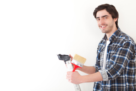 Attractive young man painting a wall in his new flatの写真素材