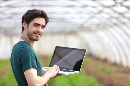 View of a Young business farmer working on his laptopの写真素材