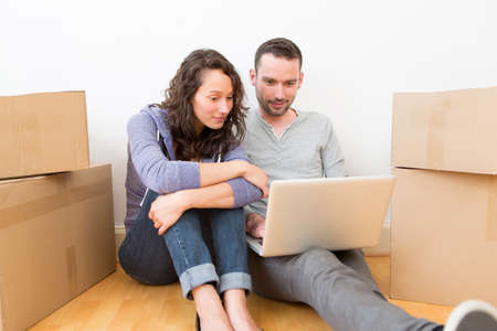 View of a Young couple using laptop while moving in new flatの写真素材