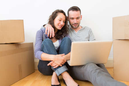 View of a Young couple using laptop while moving in new flat