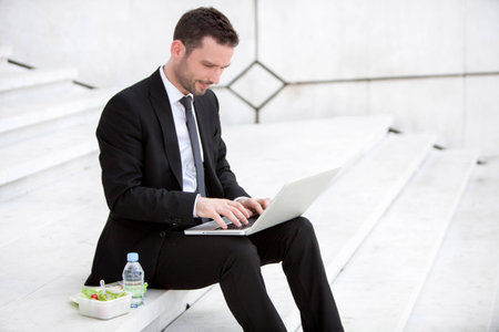Attractive businessman keep working during lunch breakの写真素材