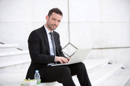 Attractive businessman keep working during lunch breakの写真素材