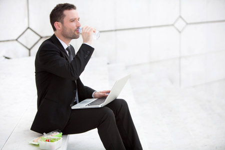 Attractive businessman keep working during lunch breakの写真素材