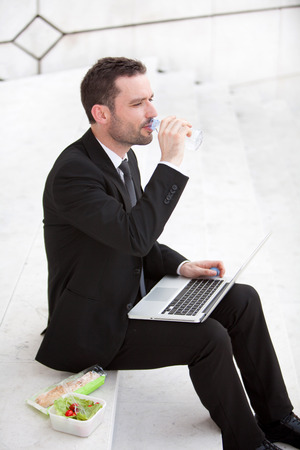 Attractive businessman keep working during lunch breakの写真素材