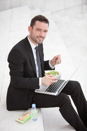 Attractive businessman keep working during lunch breakの写真素材