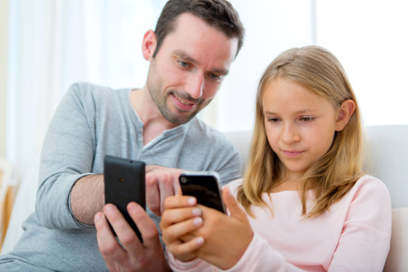 VIew of a Father and his blond daughter using mobile