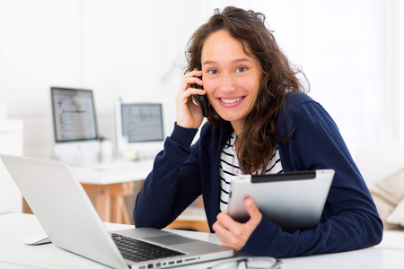View of a Young attractive woman using tablet in front of laptopの写真素材