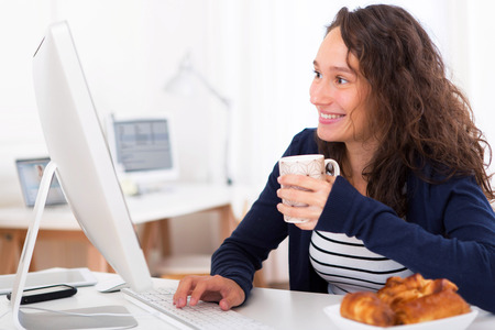 View of a Young attractive student taking breakfast while workingの写真素材