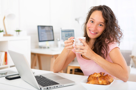 View of a Young attractive student taking breakfast while workingの写真素材